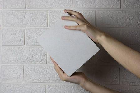Hands with an empty cardboard box on a light brick wall background.の写真素材