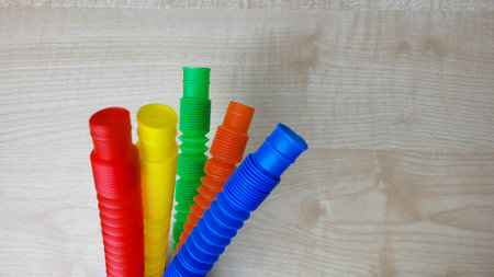A set of funny plastic multicolored tubes-antistress on a wooden backgroundの写真素材