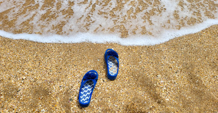 Blue slippers on the beach on the sand against the background of the seaの写真素材
