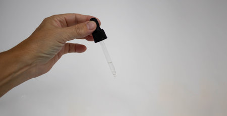 The hand of a woman holding a pipette with liquid.の写真素材