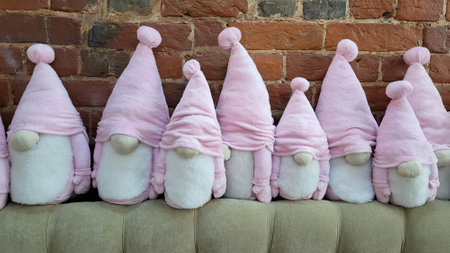 A cute family of bearded dwarfs in pink hats sits against a brick wallの写真素材