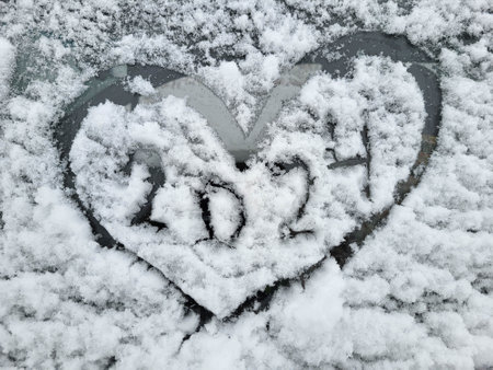 The new year is 2024. A heart painted on the windshield of a car covered with fresh Christmas snow.の写真素材