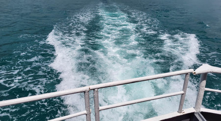 The foam trail of the sea waves behind the stern overboard of the pleasure boatの写真素材