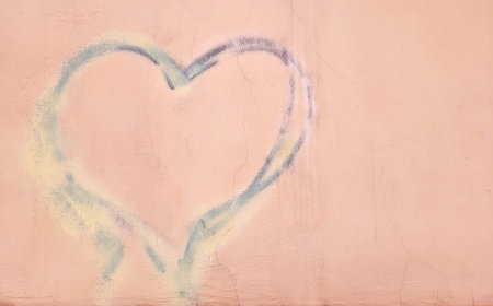 A symbol of love and romance is a heart hand-painted on the pink plaster of the wall. Background with space to copy.の写真素材