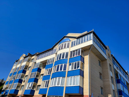 The facade of a five-storey house with blue balconies and loggias against a blue sky backgroundの写真素材