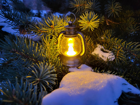 A small decorative lantern stands in the snow on the branches of a fir tree. The concept of New Year and Christmas.の写真素材
