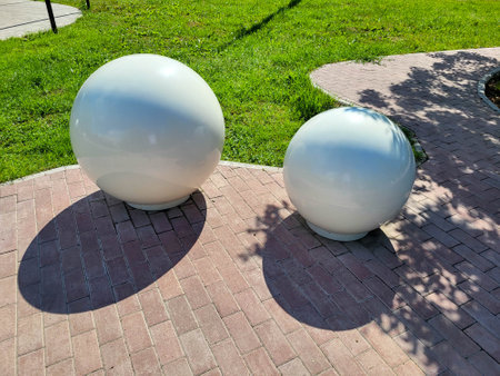 On a clear sunny day, two white decorative concrete balls can be seen in the gardenの写真素材