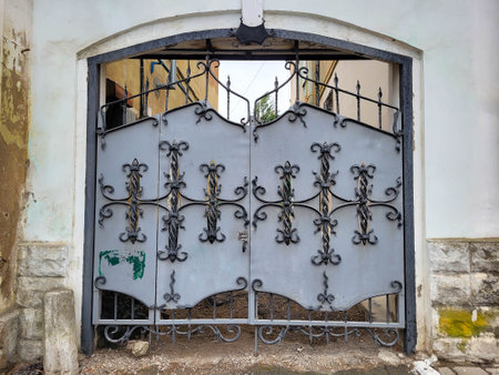 The arch of the house has a gray iron gate with wrought iron elements.
