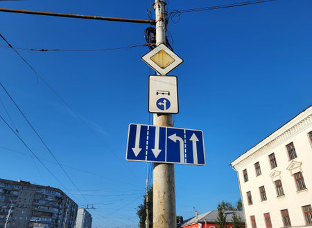 White arrows on a blue background are a standard road sign on a vertical pole against the sky.の写真素材