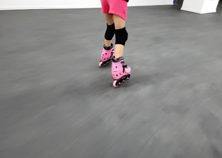 The legs of a little girl in pink roller skates walking unsteadily on the floor
