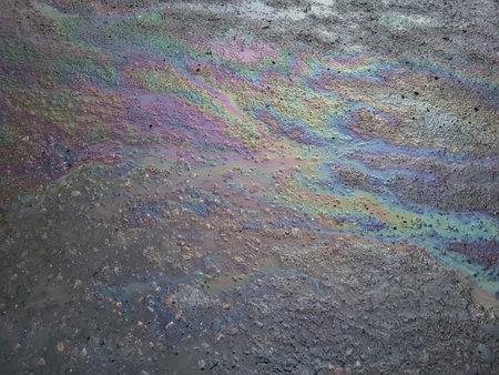A multi-colored oil stain or gasoline stain caused by a leak from under the car. The concept of environmental pollutionの写真素材