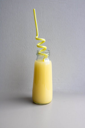 A bottle of yellow drink with a yellow straw. Cocktail Straw Day.の写真素材