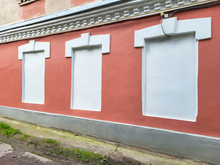 On a clear summer day, the red facade has stuccoed and white-painted window openings.の写真素材