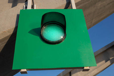 On a green shield, a traffic light with a green signal against the skyの写真素材