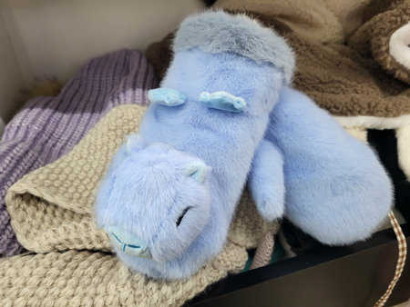 There are funny blue fur mittens shaped like a capybara on the store shelf.の写真素材