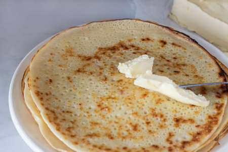 Pancakes on a plate with butter on the table
