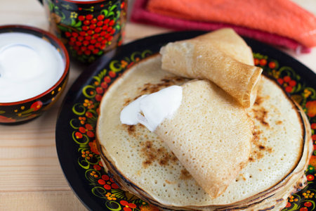 Pancakes with sour cream for a Russian wooden plate with paintingの写真素材