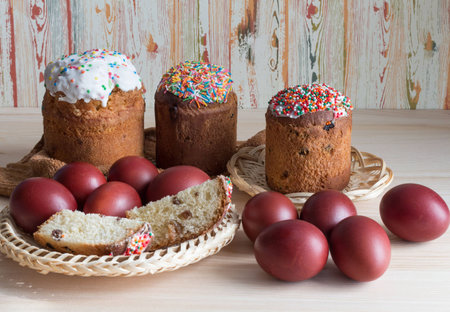 Three cakes are decorated with colored glaze, and Easter eggs in a vase on the table.の写真素材