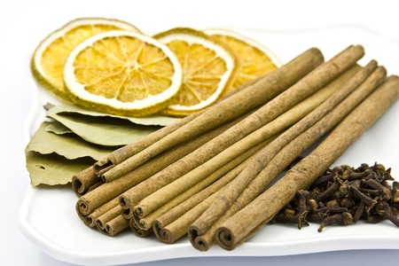 Cinnamon sticks, bay leaf, cloves, dried orange on plate