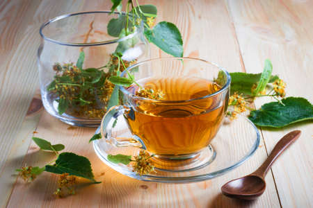 Cup with lime tea, flowers and leaves on a wooden table. The concept of health.の写真素材