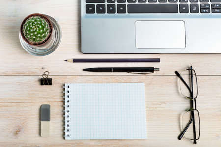 Freelancer's office workplace with laptop, notebook, stationery and office supplies, with cactus.
