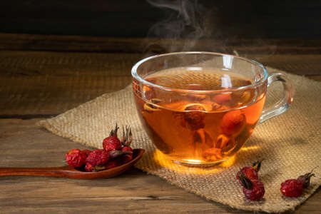 useful for health tea of the wild rose on wood surface, fruit of dogrose on sackcloth.の写真素材