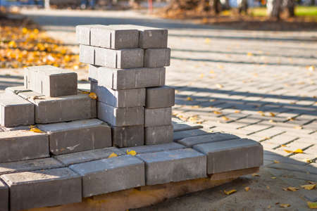Paving bricks are ready for construction work on pallets for laying paving slabs of the city square. On the street in the park autumn, leaves.の写真素材