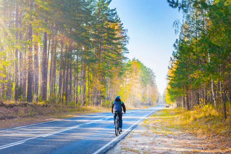 A cyclist rides under the highway. Autumn road in nature.の写真素材