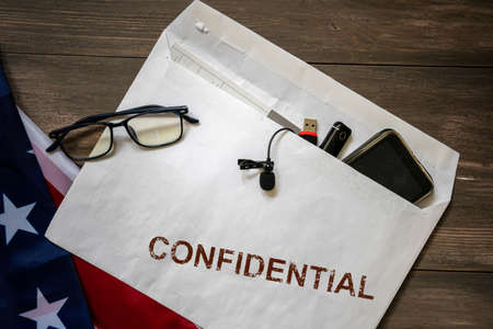 The envelope with the documents and the phone with the seal is confidential on the table. The concept of espionage and industrial security.の写真素材
