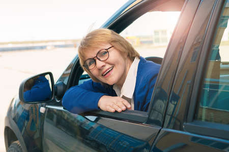 A woman driving a car. A middle-aged woman smiles.の写真素材