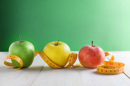 An apple on a green background and a measuring tape. The concept of a healthy lifestyle. Copy spaceの写真素材