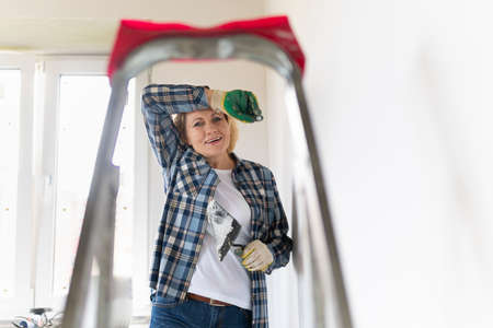 Female construction worker with a construction tool. A middle-aged woman makes repairs in the apartment.の写真素材