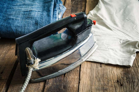 On the dark wooden countertop is an old electric ironの写真素材
