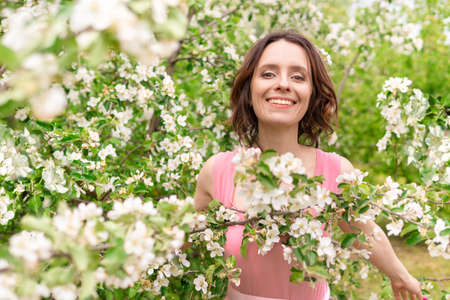A beautiful woman walks through a blooming garden. Portrait of a dark-haired female. The Apple tree...