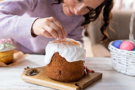 A woman holds a traditional Easter cake on the table.
