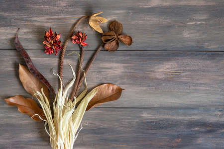 Dry flowers and plants in the composition on a wooden background.