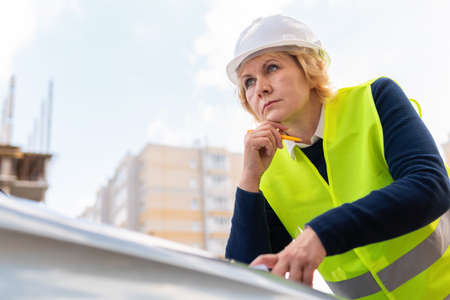 A female builder worker at a construction site works and controls the process.の写真素材