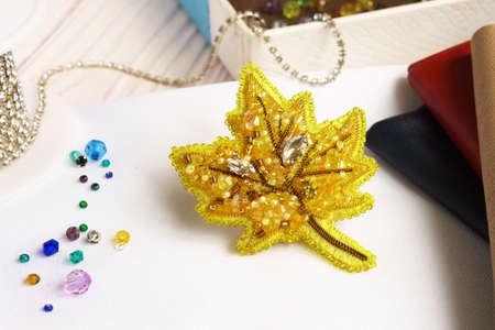 Brooch handmade made of multicolored beads on the background