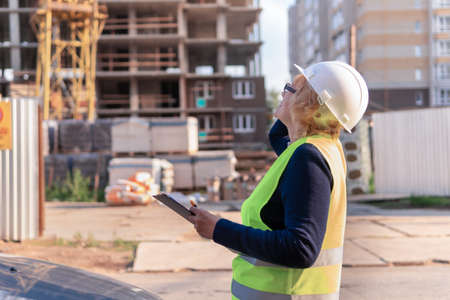 A woman Builder at a construction site inspects a buildingの写真素材