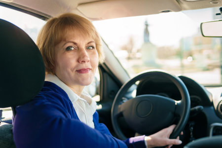A woman in a blue jacket driving a car going through the city.