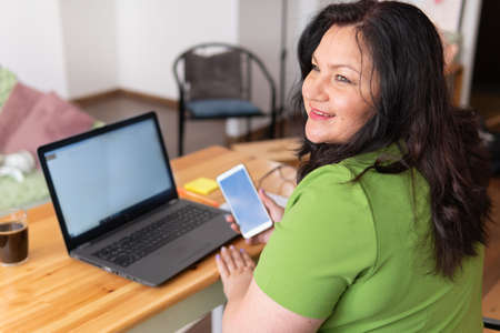 A woman sits at home at a desk, works with a laptop in social networks.