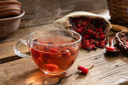 Rosehip tea on wooden background with red fruitsの写真素材