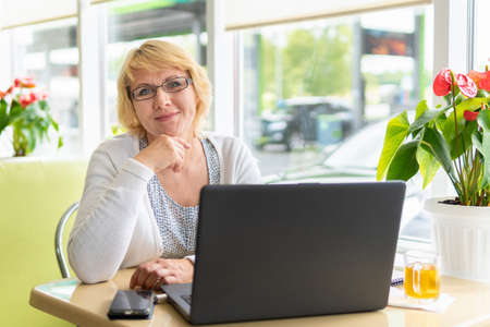 A woman with a laptop works in a cafe in the office, she is a freelancerの写真素材