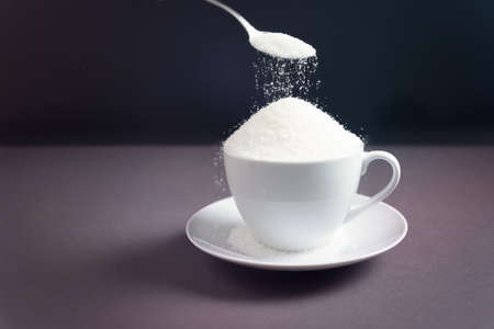 Sugar on a dark background with a spoon. Concept of harm healthの写真素材