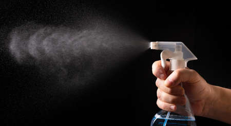 On a black background, a Hand with a spray bottle. A spray of water.の写真素材