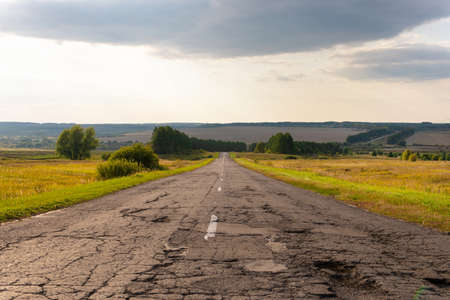 Road car without cars, around the field and forest, the sun shines.の写真素材