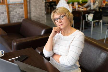 Woman with a laptop works in a cafe in the office, she is a freelancer.