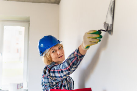 Woman Builder in the room of the house making repairs.