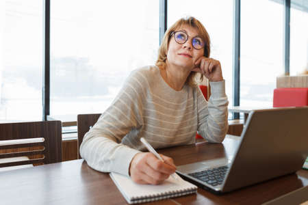 Woman in cafe and office working with laptop