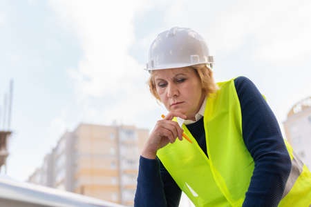 A woman Builder at a construction site inspects a building